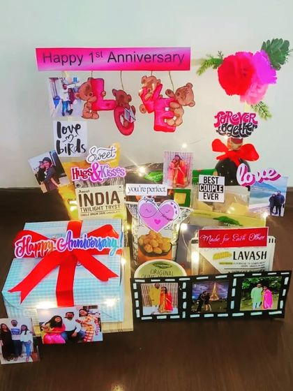 This first-anniversary hamper is lit up with fairy lights and filled with love. It features a gift box, snacks, and is personalized with photo film strips and cute 'love birds' cutouts.