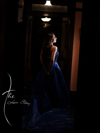 A dramatic portrait of a woman in a blue gown standing in a dark hallway, with the light catching her profile, captioned "The Love Story."