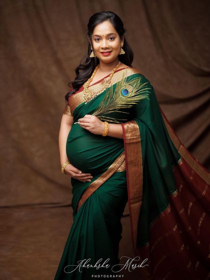 A close-up of the beautiful green and red silk saree, showing the rich texture of the fabric and the mother's serene expression.