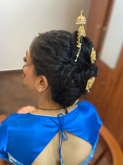 A side view of the messy Khopa bun, showing its texture and the placement of the traditional accessories.
