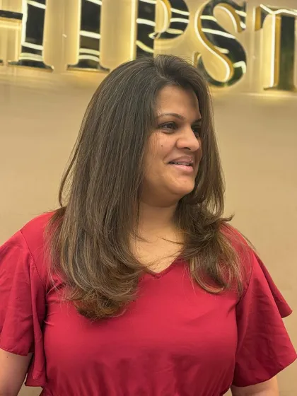 A client showing off her new hair color, which features subtle highlights on a layered cut for a fresh, modern look.