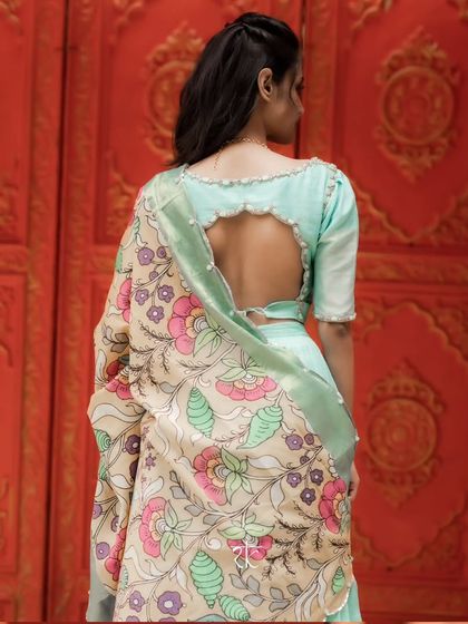 The back of the blouse features a beautiful cut-out design with pearl detailing, adding a touch of modern sophistication.