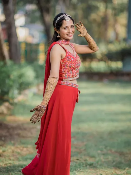 A happy and candid shot of the bride waving, her henna-adorned hands on full display.