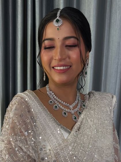 A happy, smiling portrait of the bride in her white saree, her skin glowing.