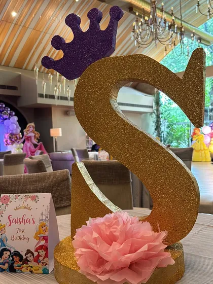 A glittering gold monogram letter 'S' with a crown, used as a centerpiece for the princess themed birthday party.