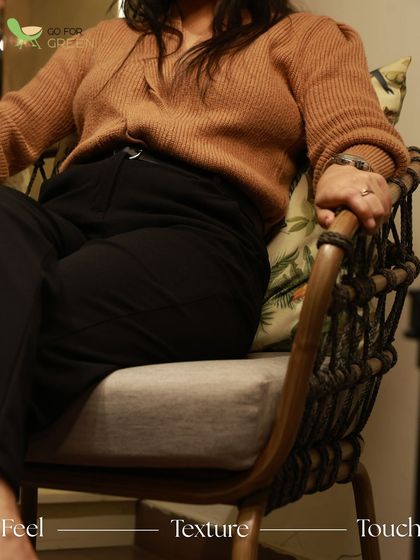 Feel the texture and touch of our Rope Chair. This close-up shows a person comfortably seated, highlighting the ergonomic design and the tactile quality of the imported rope and wooden powder-coated aluminum frame.