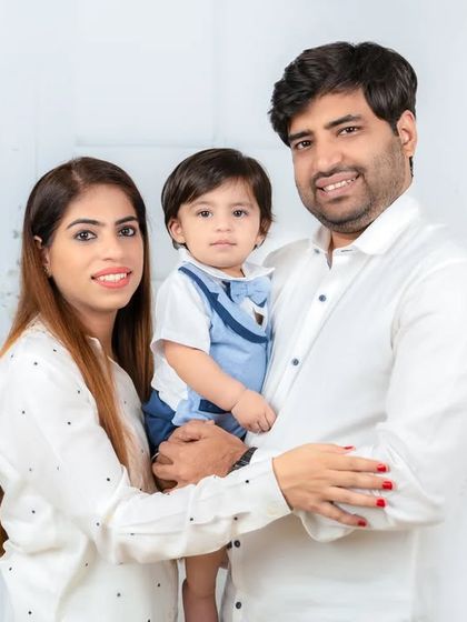 A standing family portrait showcasing the love between parents and their young child. The simple white outfits keep the focus on their happy expressions.