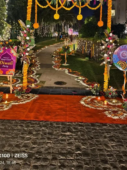 The entrance to the Diwali party, featuring a red carpet, a floral archway, and a personalized welcome sign.