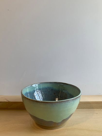 A beautiful bowl with a two-toned glaze, where a light green flows over a darker, earthy base.