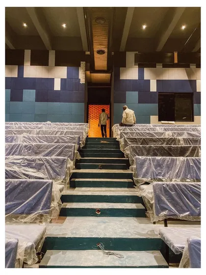 A view from the back of the auditorium shows the tiered seating and the complex geometry of the space. The design is meant to serve the local community, providing a venue for film screenings, talks, and cultural performances.