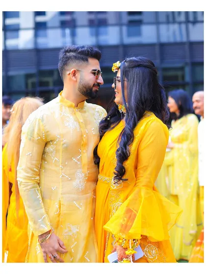 A candid moment between the couple at their Haldi function. Dressed in coordinated yellow outfits, their shared glance tells a story of love and excitement for the journey ahead.