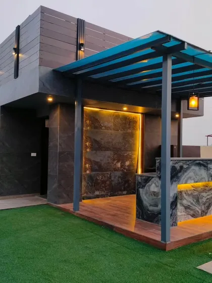 A luxurious outdoor bar in Sushant Lok, featuring a marble countertop with integrated lighting and a blue polycarbonate roof.