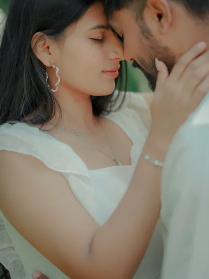 An intimate close-up where the couple touches foreheads, lost in their own world. This shot, framed by lush green leaves, feels private and deeply romantic.