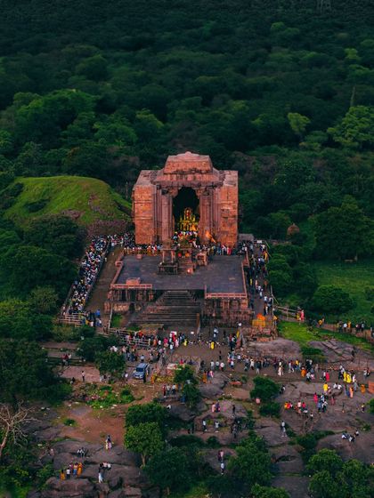 A wider aerial shot of Bhojpur Temple, showing its location amidst a lush green landscape and the crowds gathered for worship.