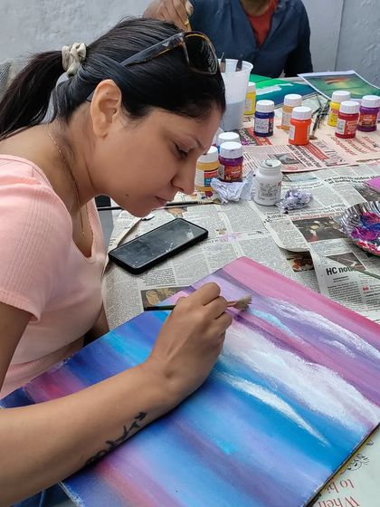 The process of creating clouds. This artist is adding layers of white to her colourful sky, a key step in landscape painting.