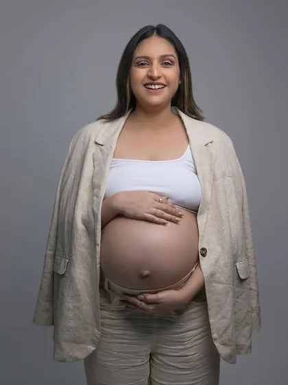 A classic maternity pose. The makeup is minimal and clean, designed to enhance her features naturally and create a timeless look for her photoshoot.