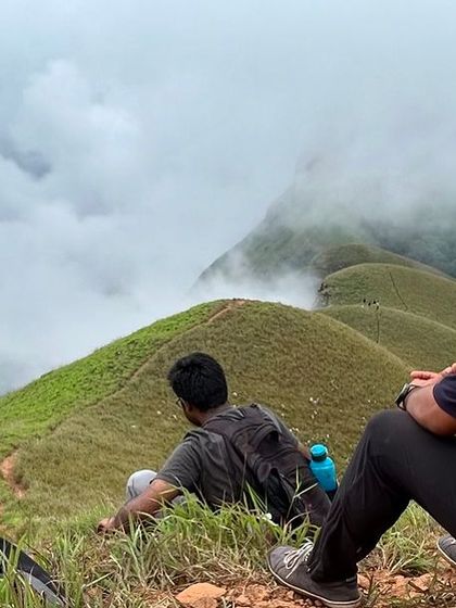 Taking a break to soak in the incredible scenery at Netravati Peak. The trek offers panoramic views of rolling green hills, often covered in a blanket of fog, creating a truly mystical atmosphere.
