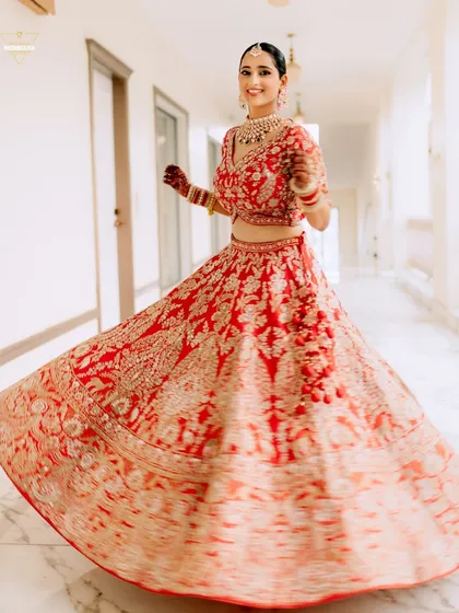 A fun and dynamic shot of the bride twirling in her red lehenga, the motion blur capturing her joy and the beautiful flare of her skirt.