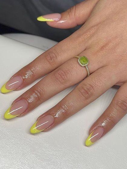 A classic French manicure with a vibrant lemon-yellow tip on almond-shaped nails, perfect for a bright, summery look.