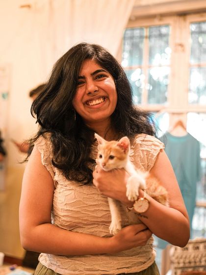 A participant holds a tiny, sleepy ginger and white kitten, a perfect picture of peace and happiness.