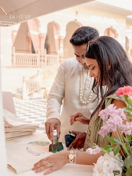 A sweet, interactive moment at a Jaipur Haldi. The couple is seen using custom block prints to create personalized keepsakes, a wonderful activity that ties into the local artistry.