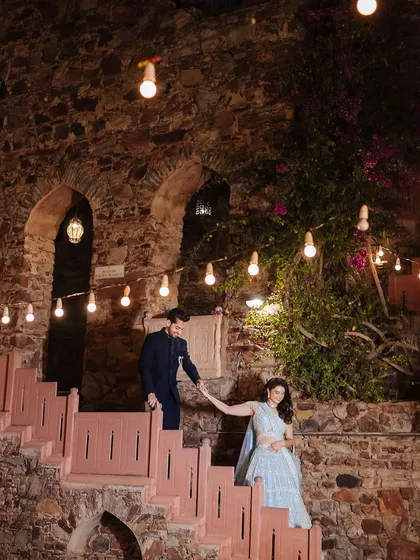 A romantic shot of a couple on a staircase at night, surrounded by the warm glow of hanging bulbs.