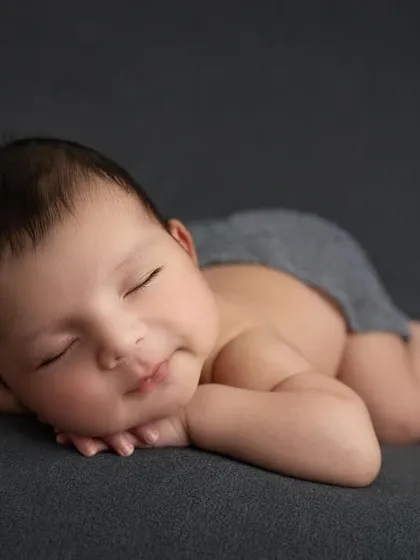 The classic 'chin on hands' pose, also known as the 'froggy' pose, is a composite image created with the utmost safety. It perfectly shows off a baby's adorable cheeks.