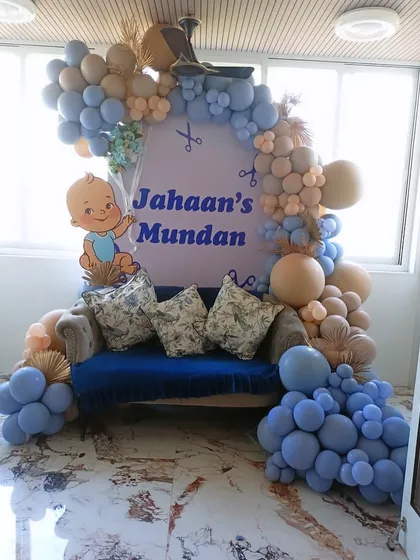 A special setup for Jahaan's Mundan ceremony. The blue and beige balloon arrangement frames a comfortable sofa, with a custom backdrop marking the occasion.