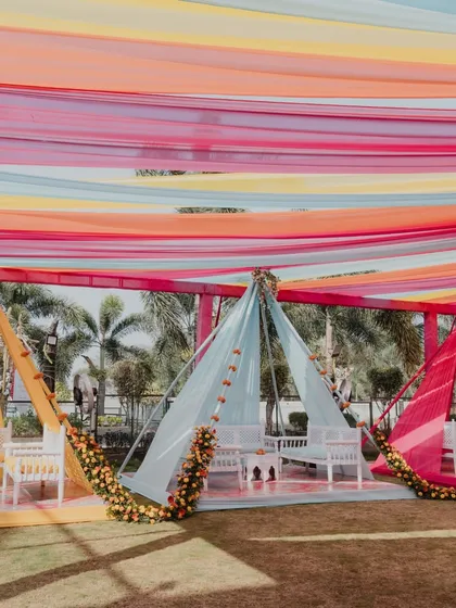 A vibrant Haldi setup with colorful drapes forming teepee-style seating areas, creating a fun and festive atmosphere.