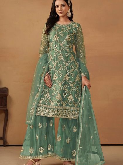 This teal-green net suit is so refreshing. The intricate sequence work and sharara style make it a trendy yet traditional choice for your next event.