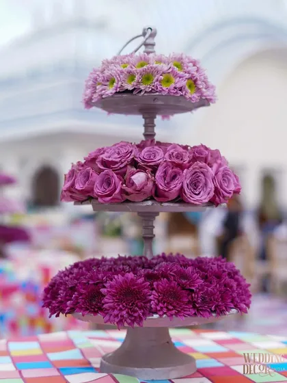 A three-tiered floral centerpiece from a vibrant Haldi event, using different shades of purple and pink flowers. This shows my versatility in creating colorful, traditional setups as well.