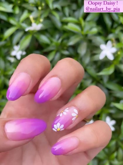 A client repost showing off her purple ombre nails with cute daisy accents.