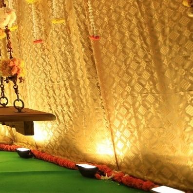 A side view of the traditional swing setup. The combination of the rich brocade backdrop, floral garlands, and warm lighting creates a perfect setting for auspicious family ceremonies.