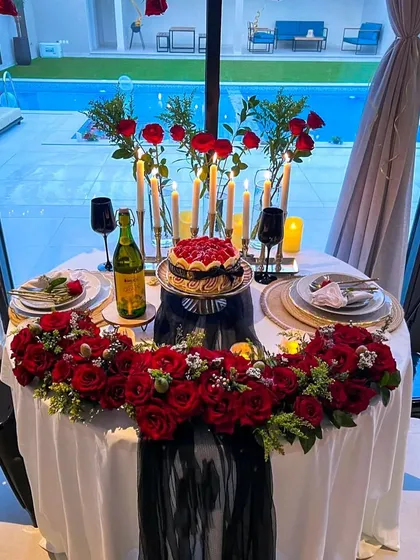 I believe romance is in the details. This poolside candlelit dinner setup shows my passion for creating a royal experience, using lush red roses, elegant tableware, and an abundance of candles to set a passionate mood.
