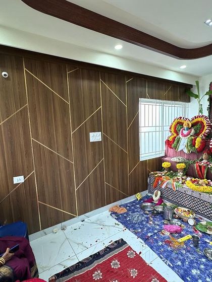 A pooja ceremony being performed in a newly designed living room. The feature wall with geometric patterns provides a modern backdrop for this traditional event.