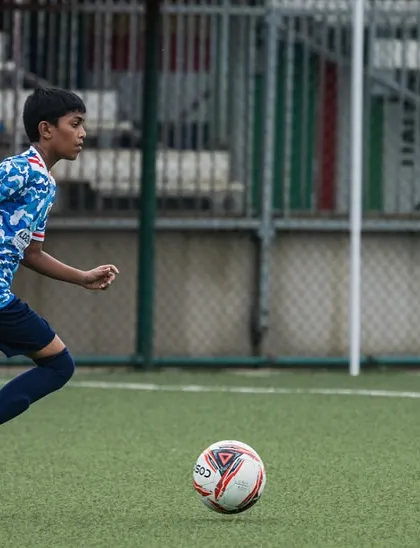 A young player from our U13 team dribbling the ball down the field during a youth league match. We train our players to be confident on the ball.