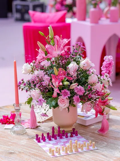 We love adding playful touches. Here, a custom pink and white chessboard sits beside a lush floral arrangement and taper candle, adding an element of fun to the elegant lounge table.