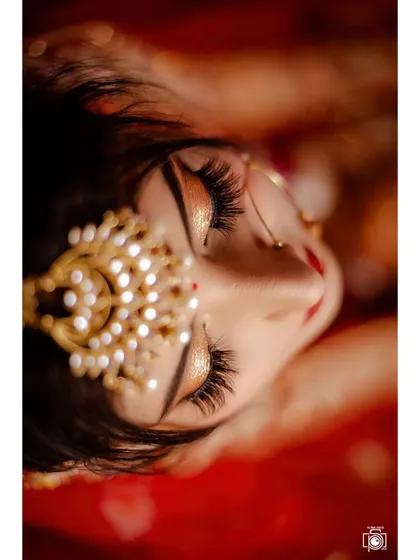 A creative top-down shot focusing on the bride's stunning eye makeup and the intricate matha patti. It's these small, precious details that make up the whole beautiful picture.
