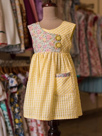 A cheerful yellow dress that combines a gingham skirt with a floral bodice. The asymmetrical design and cute pocket make this a unique and playful piece.