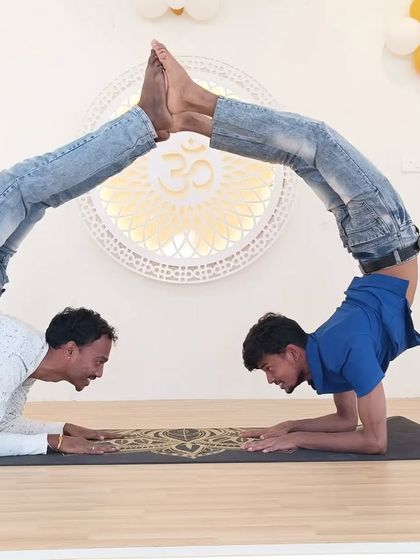 Two practitioners create a beautiful, symmetrical shape with their bodies, showcasing advanced flexibility and teamwork.