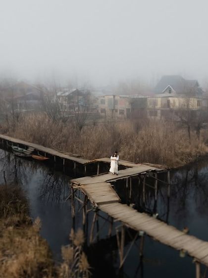 An aerial view of a lone figure on a winding wooden bridge, showcasing the unique and dramatic landscapes of Kashmir. This shot highlights our artistic vision and ability to capture breathtaking, scene-setting images.