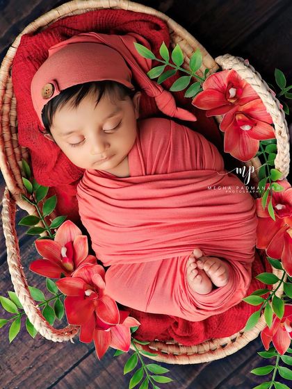 A peaceful sleeping portrait in the same coral-red setup, showing the baby's tiny feet.