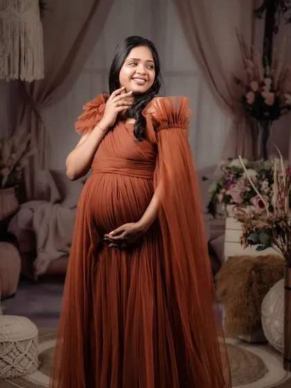 A joyful smile from a happy mom-to-be. This shot shows off the optional sleeve attachment for the rust-colored gown, showcasing its versatility and style.