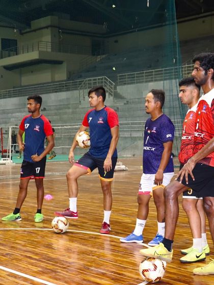Futsal players listen intently during a team huddle. Our venue provides a professional environment for teams to focus and prepare for their matches.