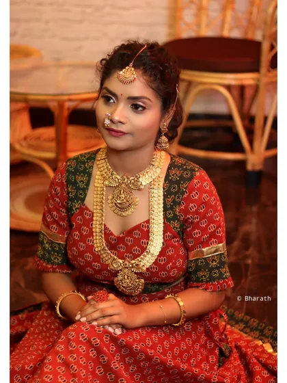 A seated portrait of a model in a full traditional lehenga and jewelry. The pose is classic and elegant, perfect for a bridal or ethnic wear catalog.