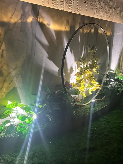 A close-up of the lit garden feature, showing how light and shadow play on the artificial plants.