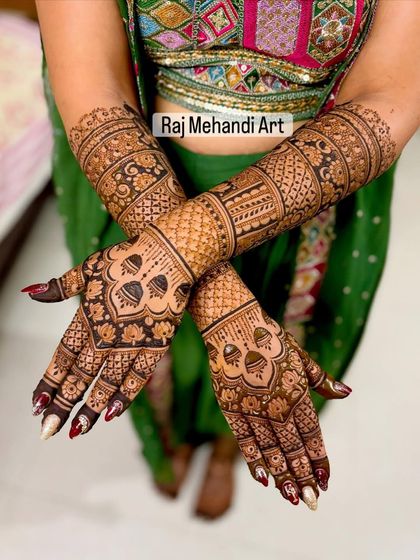 A beautifully balanced design with matching patterns on both hands. The mehndi extends up to the mid-forearm, featuring traditional motifs and checkerboard patterns for a full look.