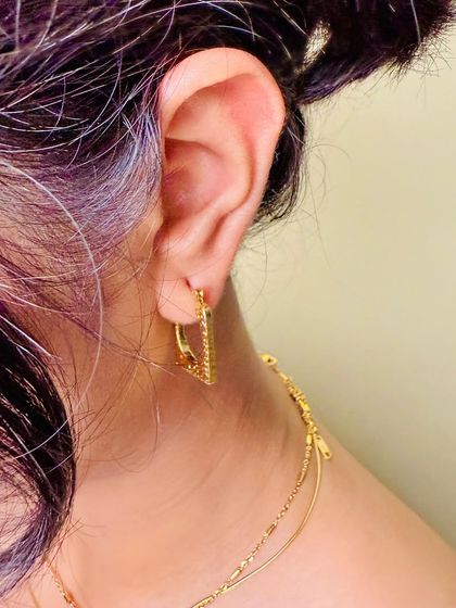A tight, detailed shot of a gold hoop earring being worn. This perspective is perfect for product listings, giving customers a clear view of how the earring sits and its size.