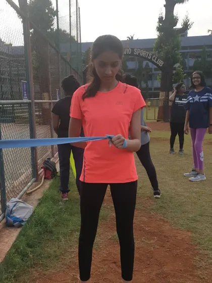 An athlete uses a blue theraband for an upper body strengthening exercise. Resistance bands are a versatile tool we use to build strength in the shoulders and back, which is important for maintaining proper running form.