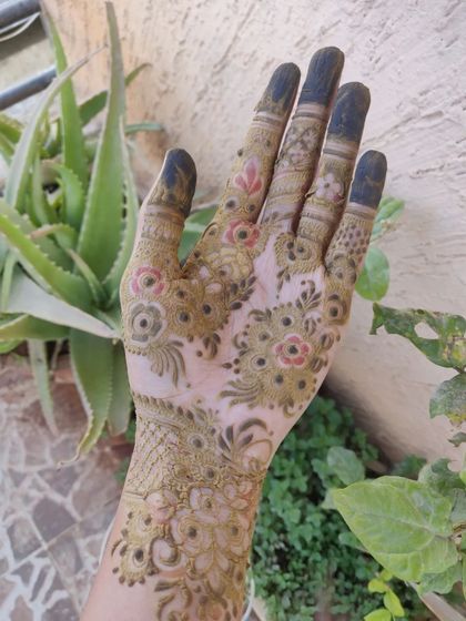 This is the henna paste freshly applied. The design is a mix of floral and geometric patterns, and at this stage, the paste is a dark greenish-brown.
